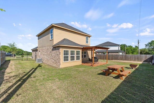 back of property featuring a yard, brick siding, a fenced backyard, and a shingled roof