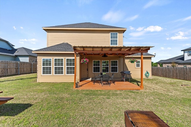 back of house featuring a yard, a deck, a fenced backyard, and a ceiling fan