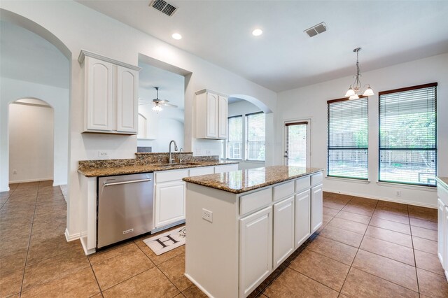 kitchen featuring dishwasher, a sink, a center island, a ceiling fan, and arched walkways