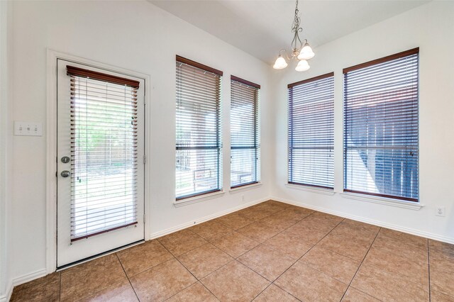 unfurnished dining area featuring a chandelier, light tile patterned flooring, and baseboards