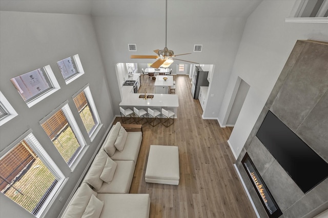 3506 Riley St, Fate, TX 75087 - living area featuring a glass covered fireplace, visible vents, ceiling fan, high vaulted ceiling, and wood finished floors