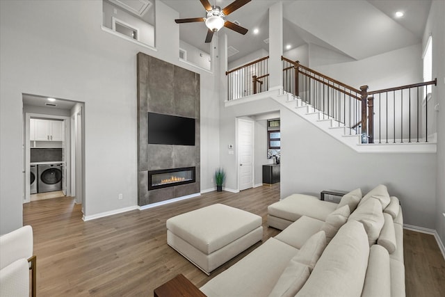 3506 Riley St, Fate, TX 75087 - living room with a towering ceiling, baseboards, a tiled fireplace, a ceiling fan, and wood finished floors
