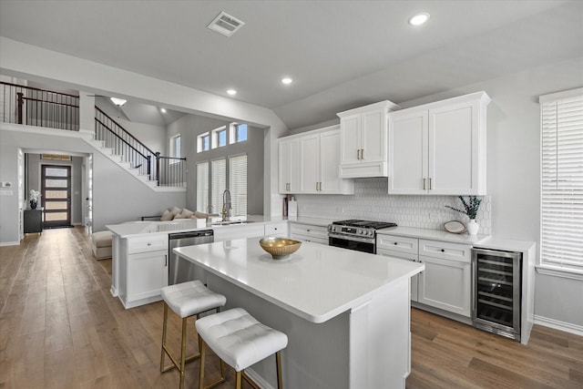 3506 Riley St, Fate, TX 75087 - kitchen with visible vents, appliances with stainless steel finishes, a peninsula, under cabinet range hood, and beverage cooler
