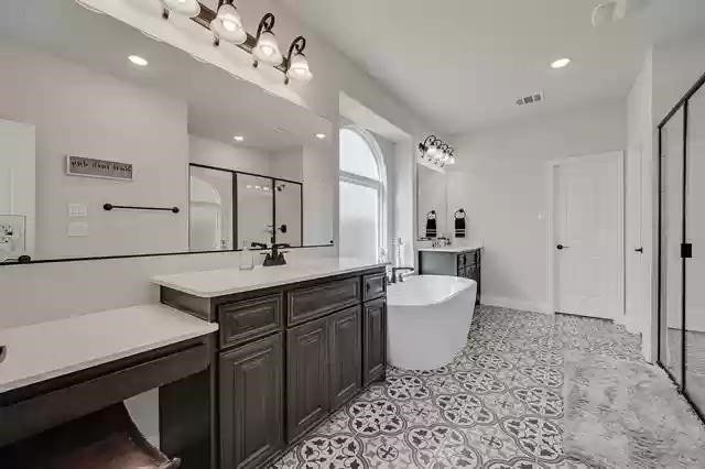 9812 El Colina Dr, Fort Worth, TX 76179 - bathroom featuring two vanities, a stall shower, a sink, a freestanding bath, and tile patterned floors
