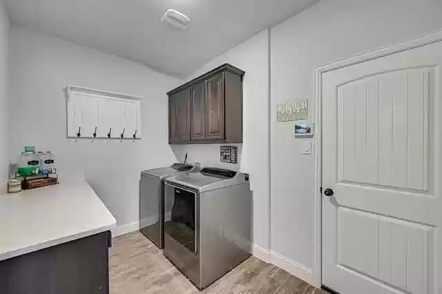 9812 El Colina Dr, Fort Worth, TX 76179 - laundry room with washer and dryer, light wood-type flooring, baseboards, and cabinet space