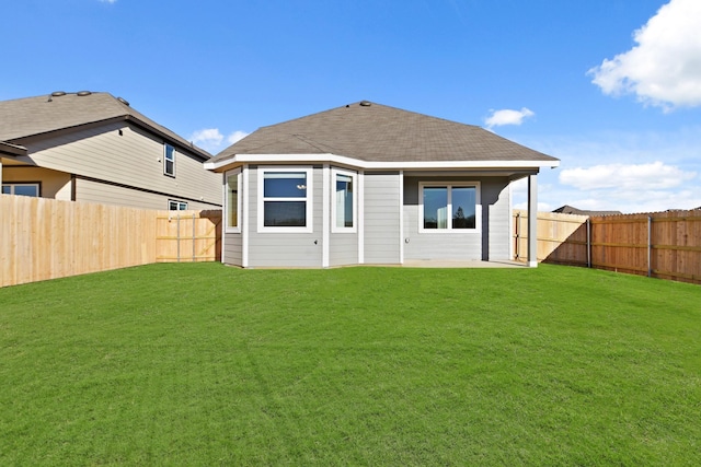 rear view of house with a lawn, a shingled roof, and a fenced backyard