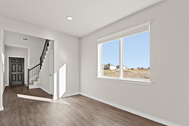 interior space with stairs, baseboards, visible vents, and wood finished floors
