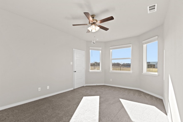 empty room featuring a healthy amount of sunlight, carpet flooring, a ceiling fan, and visible vents