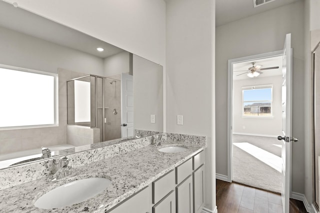 bathroom featuring a stall shower, ceiling fan, a sink, and wood finished floors