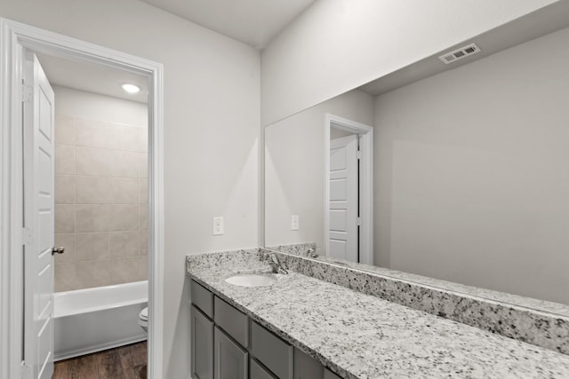 full bath with toilet, wood finished floors, shower / washtub combination, visible vents, and vanity