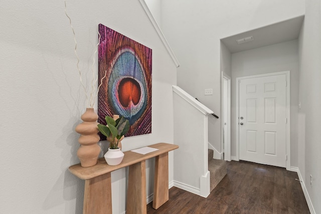hallway with dark wood-type flooring, baseboards, and stairway