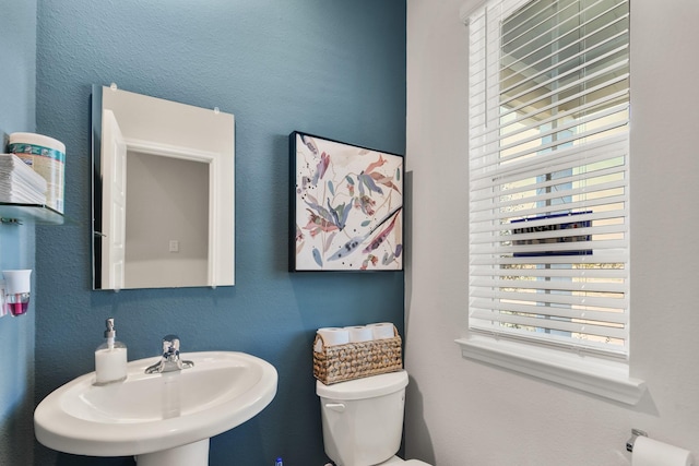 half bathroom featuring a sink, toilet, and plenty of natural light