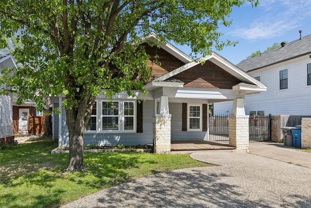 view of front of home with a front yard, a porch, driveway, and fence