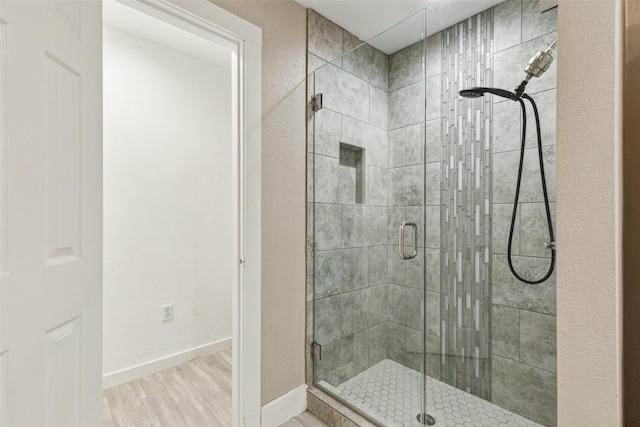 bathroom featuring baseboards, a stall shower, and wood finished floors