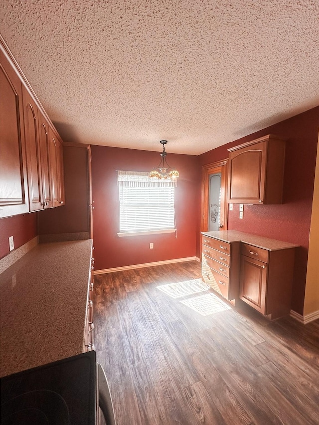 unfurnished dining area with a chandelier, a textured ceiling, baseboards, and dark wood finished floors