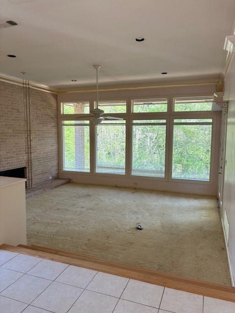 1417 Wyndmere Dr, Desoto, TX 75115 - carpeted empty room featuring tile patterned flooring, crown molding, a brick fireplace, visible vents, and ceiling fan