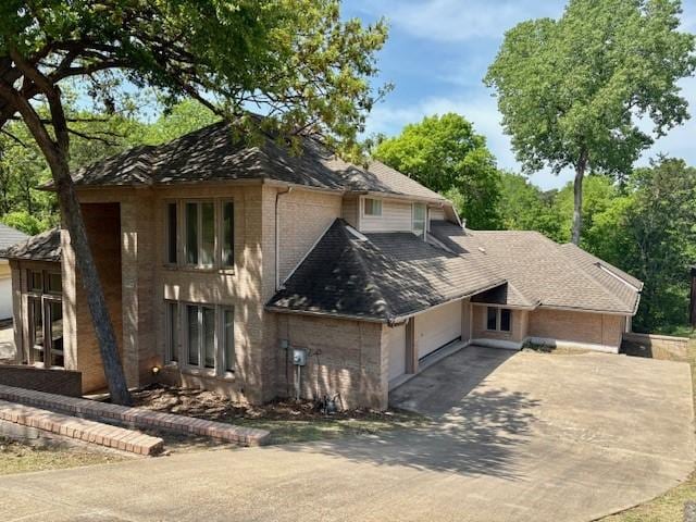 1417 Wyndmere Dr, Desoto, TX 75115 - view of side of home featuring an attached garage, roof with shingles, driveway, and brick siding