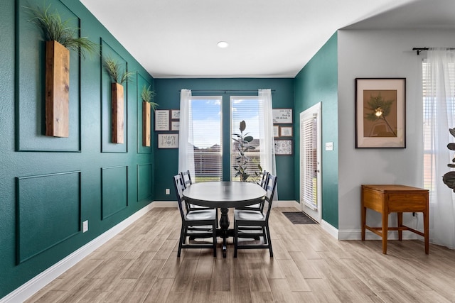 dining room featuring light wood-type flooring, baseboards, and a healthy amount of sunlight
