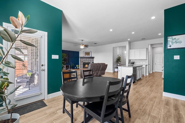 dining room with baseboards, recessed lighting, a fireplace, ceiling fan, and light wood finished floors