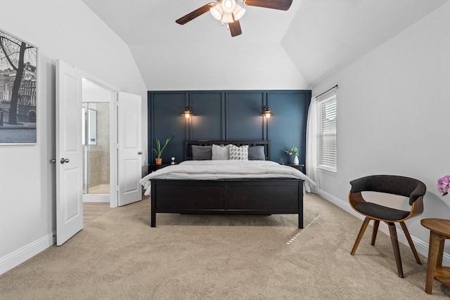 bedroom with ensuite bathroom, light colored carpet, vaulted ceiling, and a ceiling fan
