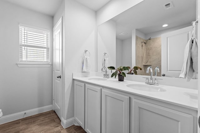 bathroom with double vanity, baseboards, a sink, and wood finished floors