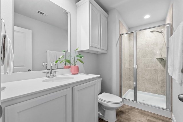 bathroom with vanity, a stall shower, toilet, visible vents, and wood finished floors