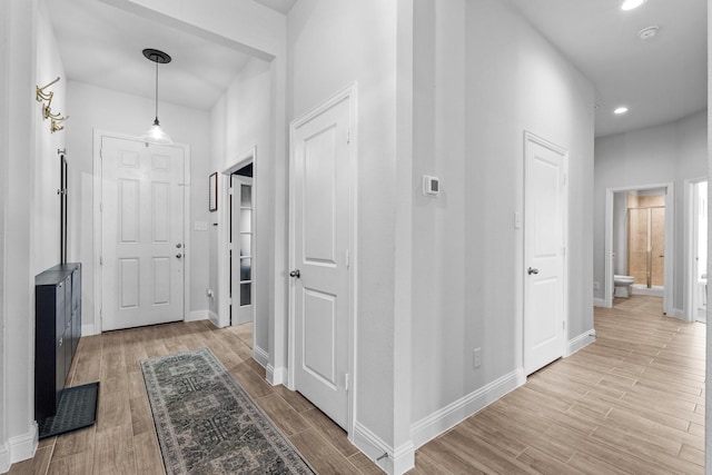 corridor featuring recessed lighting, light wood-style flooring, and baseboards