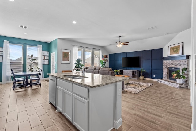 kitchen featuring a ceiling fan, vaulted ceiling, visible vents, a healthy amount of sunlight, and a sink