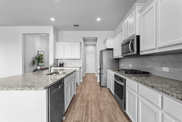 kitchen with light wood-style floors, visible vents, appliances with stainless steel finishes, a kitchen island with sink, and a sink