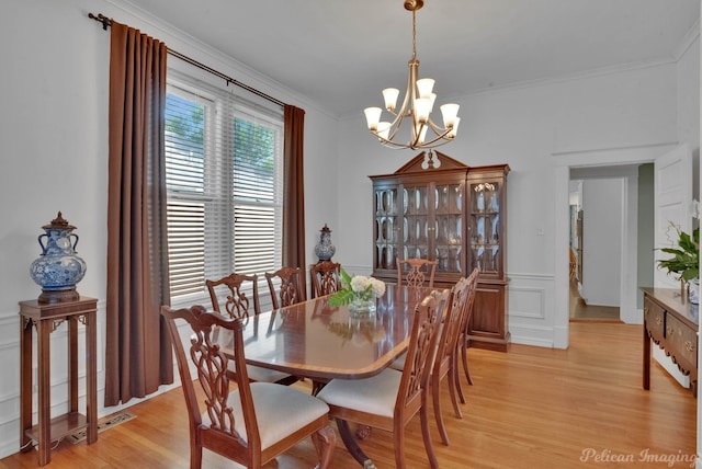 dining space with a chandelier, a decorative wall, light wood-style flooring, and crown molding