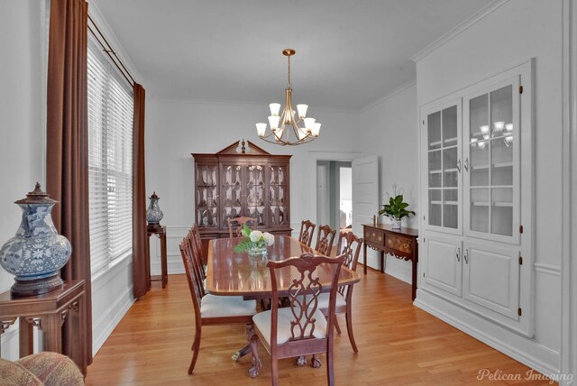dining space featuring crown molding, an inviting chandelier, and light wood-style floors