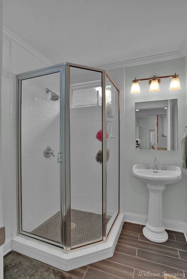 full bathroom featuring baseboards, a stall shower, ornamental molding, and wood finish floors