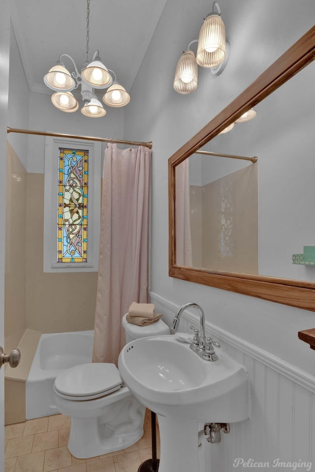 bathroom with an inviting chandelier, a sink, toilet, shower / tub combo with curtain, and tile patterned floors