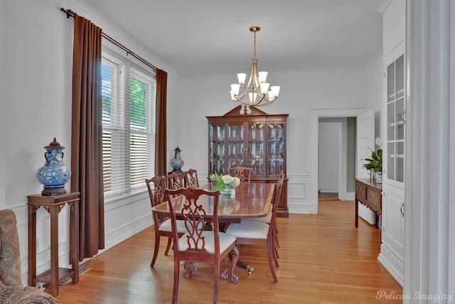 dining area with a chandelier, light wood-style floors, and ornamental molding