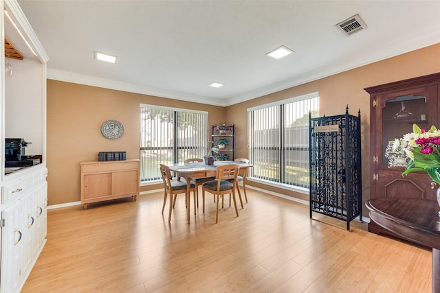 dining area featuring baseboards, visible vents, light wood-type flooring, and crown molding