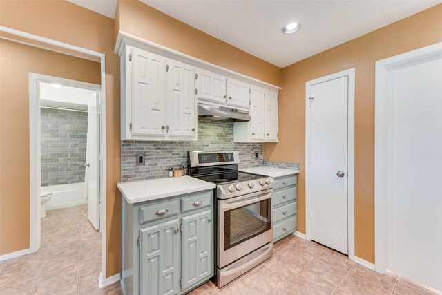 kitchen with light countertops, electric range, under cabinet range hood, white cabinetry, and light tile patterned flooring
