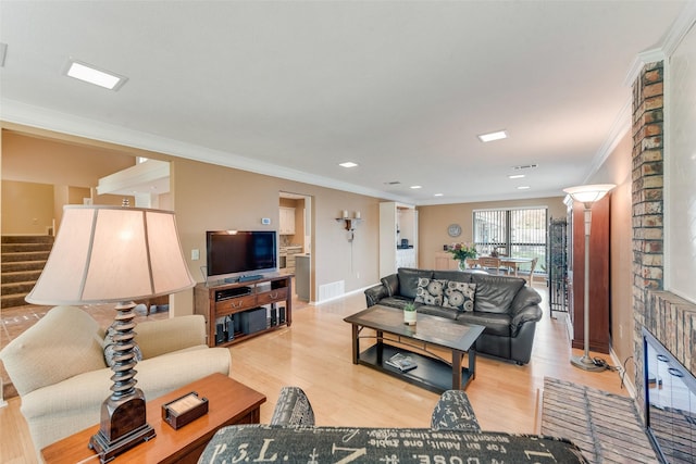 living area featuring visible vents, baseboards, ornamental molding, and light wood-style flooring