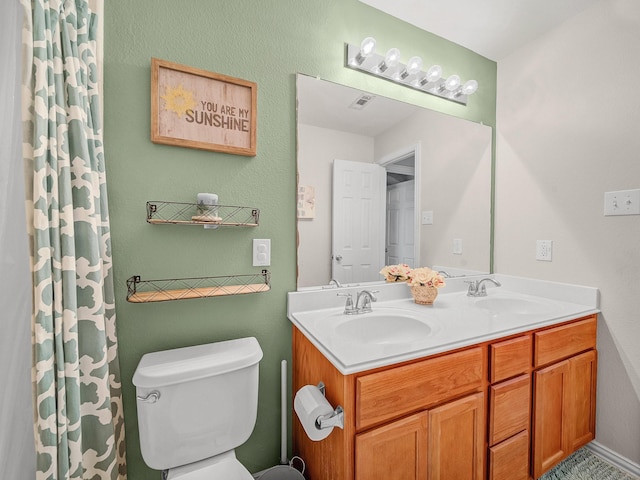 bathroom with a sink, visible vents, toilet, and double vanity