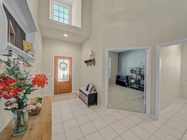foyer entrance featuring light tile patterned floors, baseboards, a high ceiling, and a healthy amount of sunlight