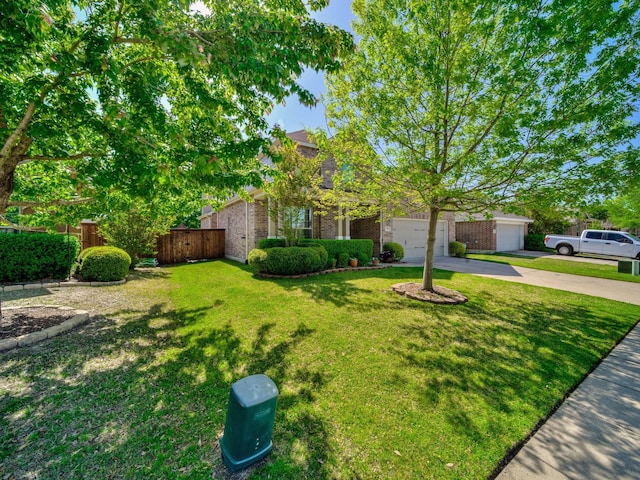 obstructed view of property with driveway, an attached garage, a front yard, brick siding, and fence