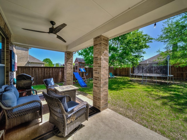 view of patio / terrace with a trampoline, a fenced backyard, a playground, and a ceiling fan