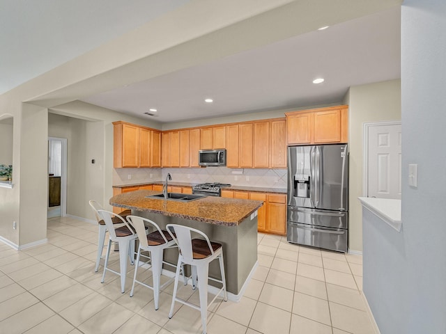 kitchen with light tile patterned floors, a sink, backsplash, and appliances with stainless steel finishes