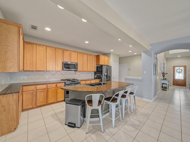 kitchen with visible vents, arched walkways, a sink, stainless steel appliances, and backsplash