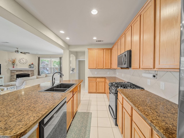 kitchen featuring black appliances, visible vents, a brick fireplace, a sink, and light brown cabinetry