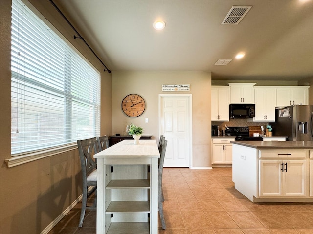 kitchen with visible vents, light tile patterned floors, dark countertops, black appliances, and decorative backsplash