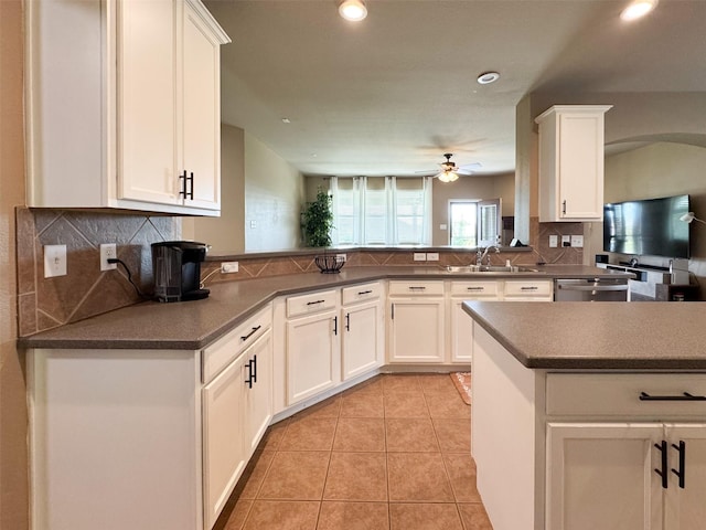 kitchen featuring tasteful backsplash, a peninsula, a ceiling fan, white cabinets, and a sink
