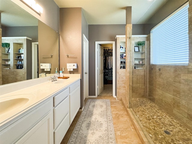bathroom featuring a sink, a spacious closet, a walk in shower, and double vanity