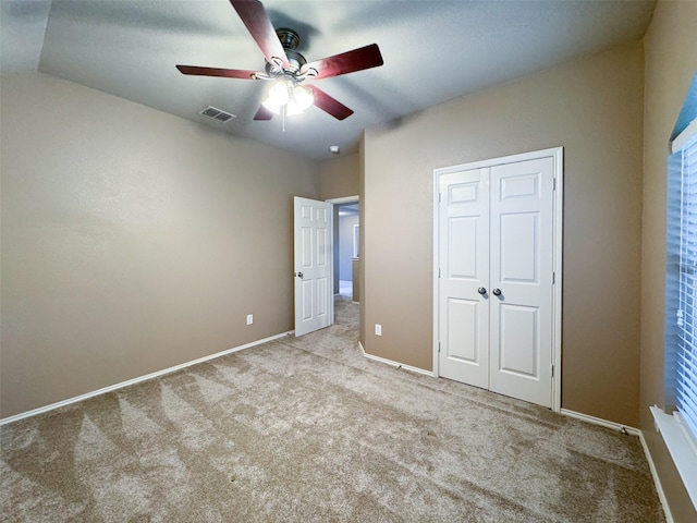 unfurnished bedroom with visible vents, baseboards, a closet, a ceiling fan, and carpet flooring