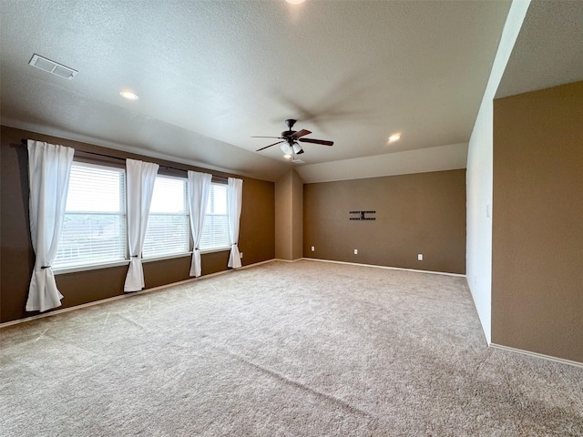 carpeted spare room with a textured ceiling, ceiling fan, baseboards, and visible vents