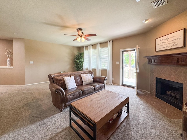 carpeted living area featuring visible vents, baseboards, a ceiling fan, and a tile fireplace